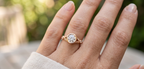 Model hand wearing a 2 CT round cut lab grown diamond vintage bezel ring in rose gold with leaf filigree shoulders.
