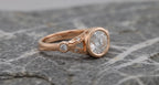 Three-quarter profile showcasing the smooth rose gold bezel frame and delicate split leaf shoulder design