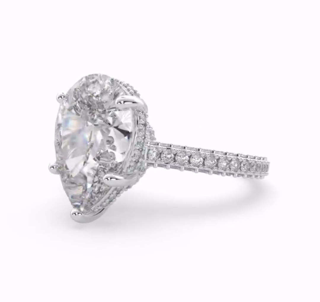 Side view of a 4 carat pear cut lab grown diamond engagement ring with a hidden halo and pavé band.