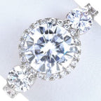 Top view of a 3 carat round lab grown diamond three-stone engagement ring with halo setting and pavé band.