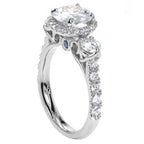 Angled side view showing the pavé band, three-stone setting, and blue sapphire accent under the gallery.
