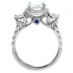 Direct profile view of the ring displaying delicate scrollwork and a bezel-set blue sapphire surprise detail.