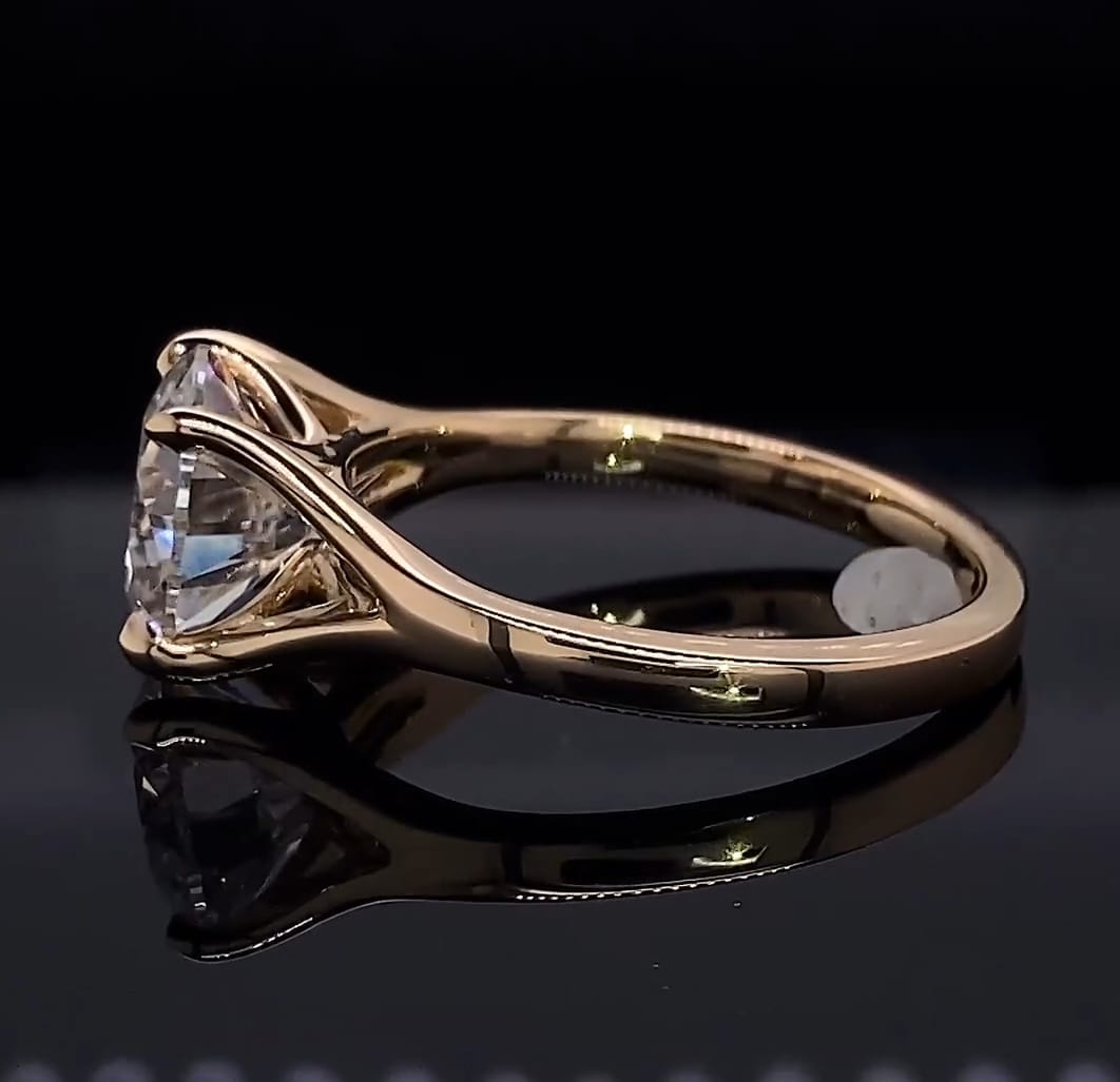 Direct profile view showing the architectural prongs and smooth gold band of a round diamond engagement ring.