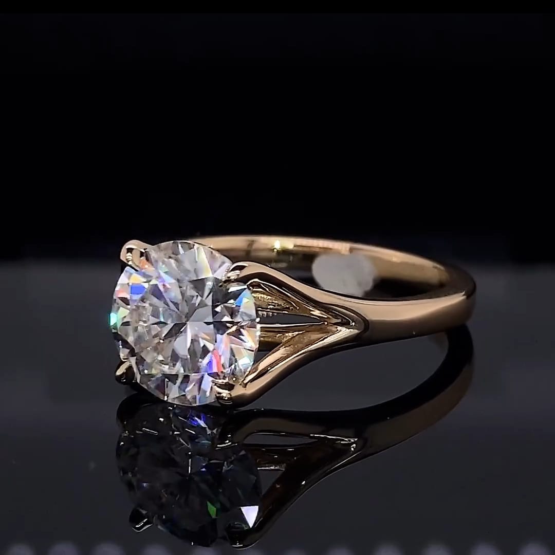 Three-quarter view of a 3 carat round lab diamond solitaire ring resting on a reflective black surface.