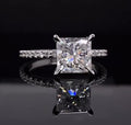 Straight-on view of a square princess cut lab grown diamond ring resting on a reflective dark surface