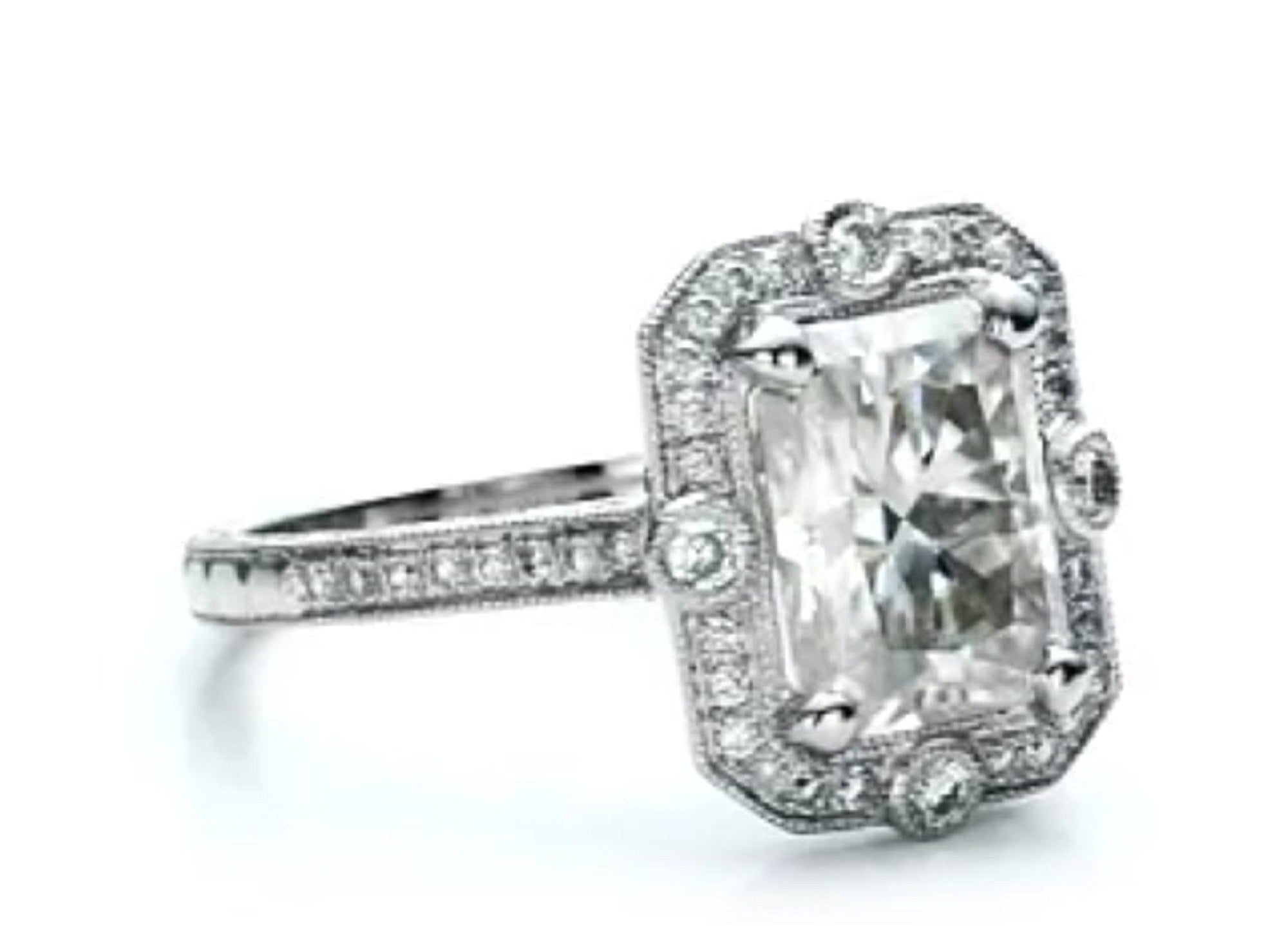 Three-quarter view displaying the radiant cut center diamond and milgrain halo setting on a white background.