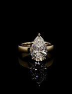 Front facing view of a 3 carat pear cut lab grown diamond engagement ring with a high-polish yellow gold band.