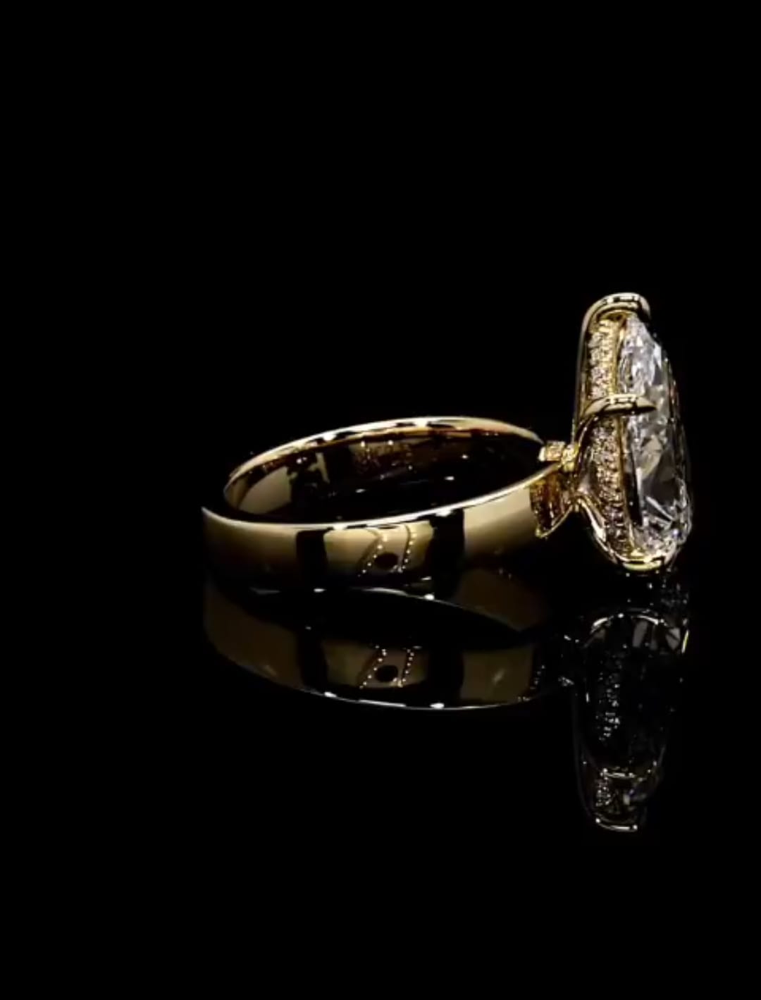 Side angle detailing the micro-pavé hidden halo basket and polished gold shank profile of a pear solitaire ring.