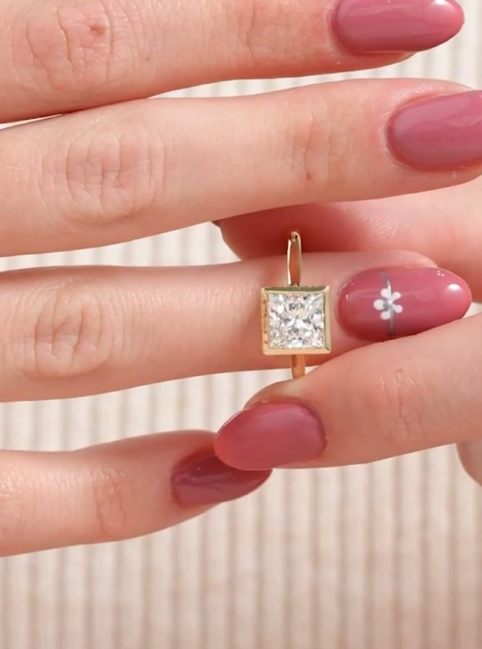 3 carat square princess cut lab diamond bezel ring held on hand showcasing its clean geometric setting.