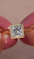 Top-down close-up view of a brilliant 3 CT princess cut lab grown diamond in a full yellow gold bezel frame.