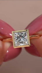 Top-down close-up view of a brilliant 3 CT princess cut lab grown diamond in a full yellow gold bezel frame.