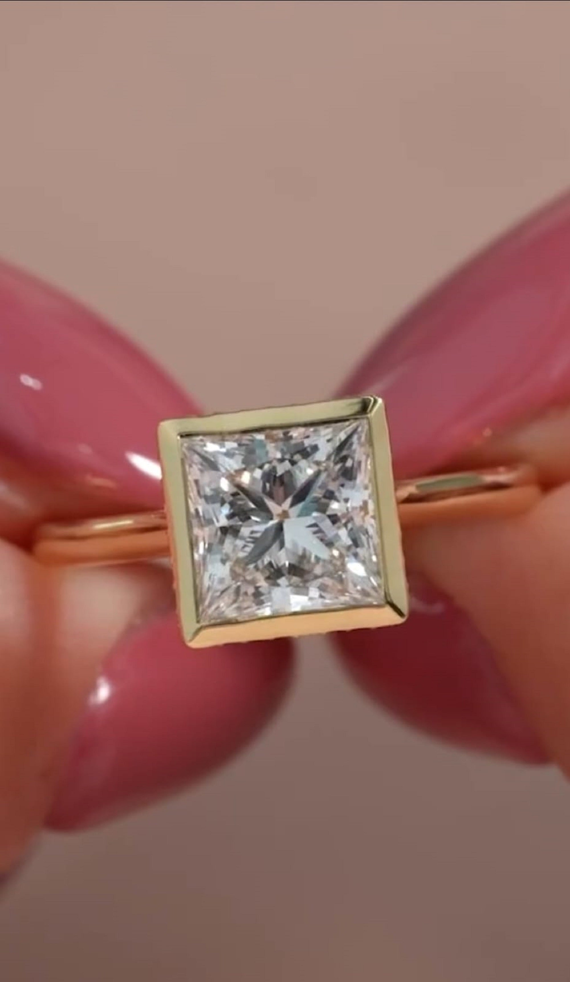 Top-down close-up view of a brilliant 3 CT princess cut lab grown diamond in a full yellow gold bezel frame.