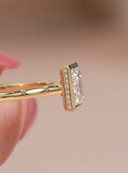 Close-up profile view of yellow gold band and pavé diamond detailing under the bezel of a princess cut ring.