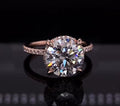Front view of a 4 carat round cut lab grown diamond engagement ring with claw prongs and rose gold pave band