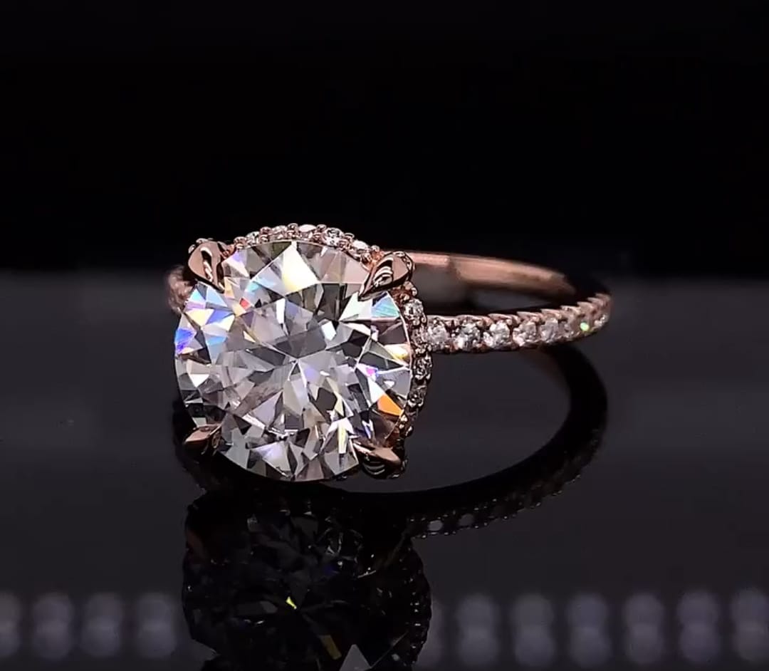 Three-quarter top angle showing a 4 carat round lab diamond ring on a black reflective surface