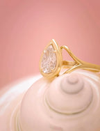 Side profile highlighting the sweeping gold split-shank curves holding a 3 carat pear cut lab diamond