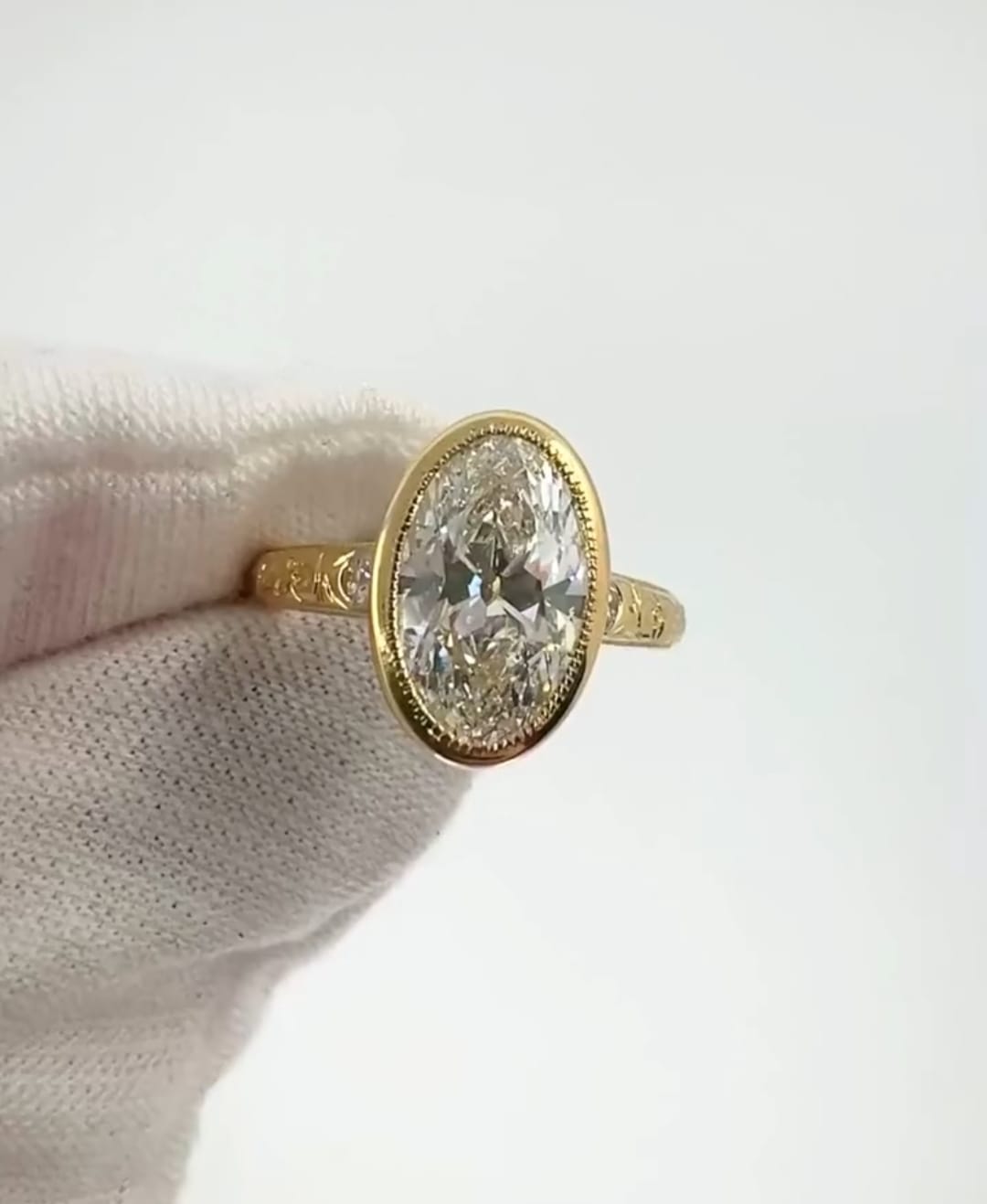 Top view showing a large 4 carat oval lab grown diamond set in a gold milgrain bezel ring