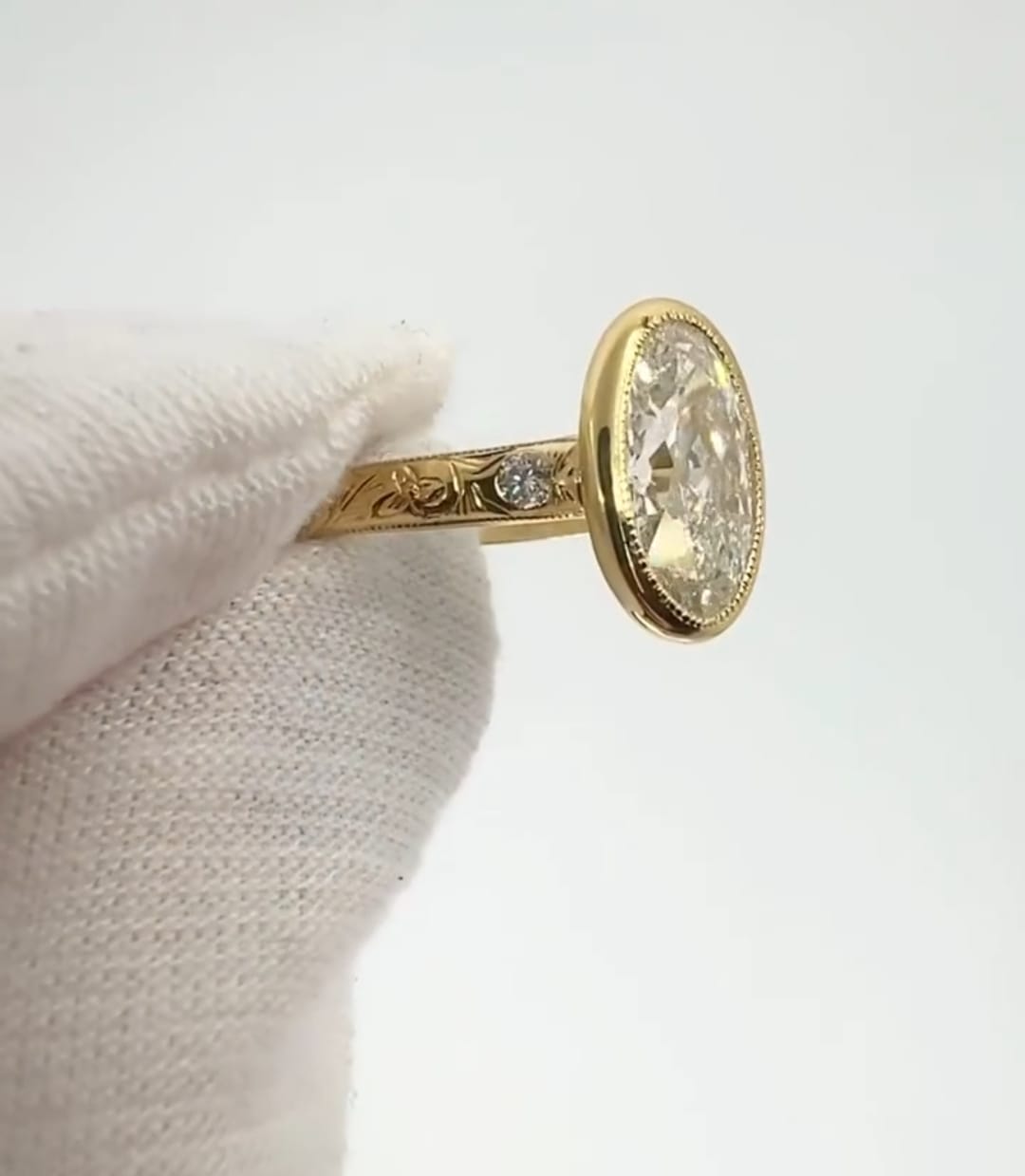 Profile view highlighting the hand-carved floral engraving and side diamond on the yellow gold ring band