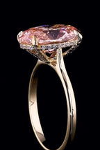Side profile view of a 3 carat fancy pink oval lab grown diamond engagement ring with a micro pave hidden halo in yellow gold