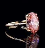 Angled profile view of a 3 carat oval pink lab created diamond ring on a delicate yellow gold band