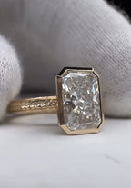 Front view showing a large 5 carat radiant lab grown diamond set in a smooth yellow gold bezel setting