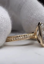 Close up of the intricate hand engraved chevron pattern on the yellow gold band of a bezel engagement ring