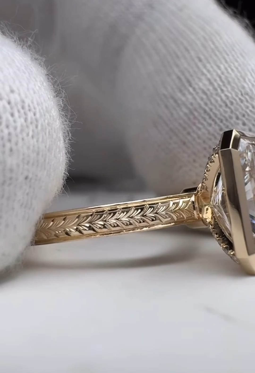 Close up of the intricate hand engraved chevron pattern on the yellow gold band of a bezel engagement ring