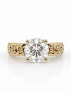 Front view of a 3 CT round brilliant cut lab-grown diamond engagement ring set in a yellow gold vintage band with detailed filigree scrollwork engraving.