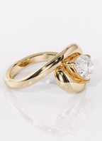 Angled side profile of a 2 carat pear cut lab grown diamond ring in a chunky yellow gold swirl bypass setting