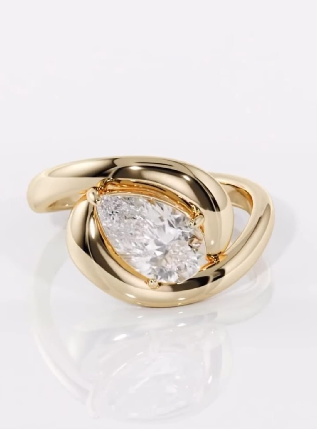 Angled top view showing the full sparkle of a 2 CT pear lab diamond framed by a chunky yellow gold setting
