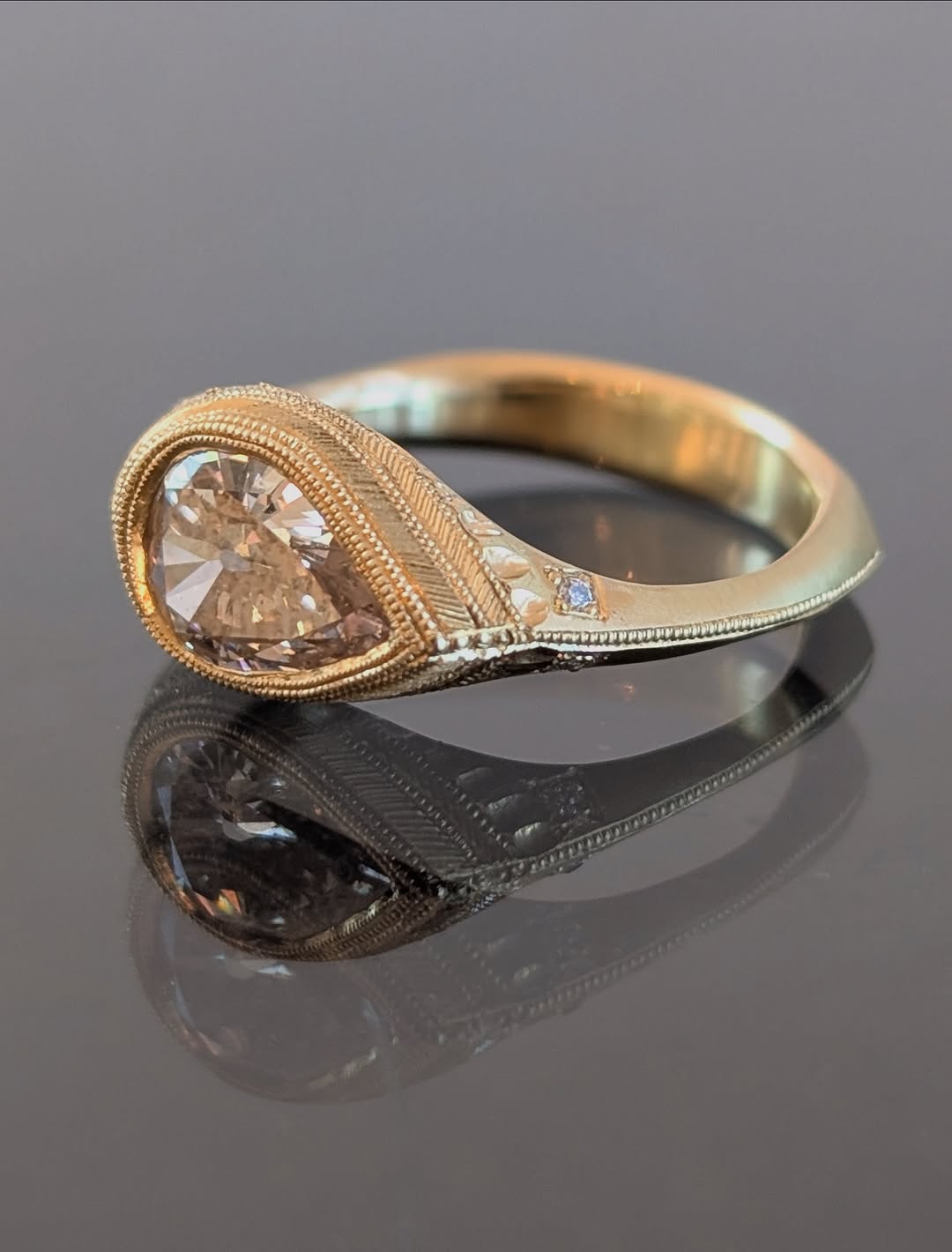 vintage 2 CT pear lab diamond ring displaying intricate band engraving and milgrain bezel