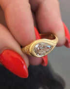 Close-up top perspective of a 2 carat pear cut lab grown diamond set in an antique-inspired yellow gold milgrain bezel