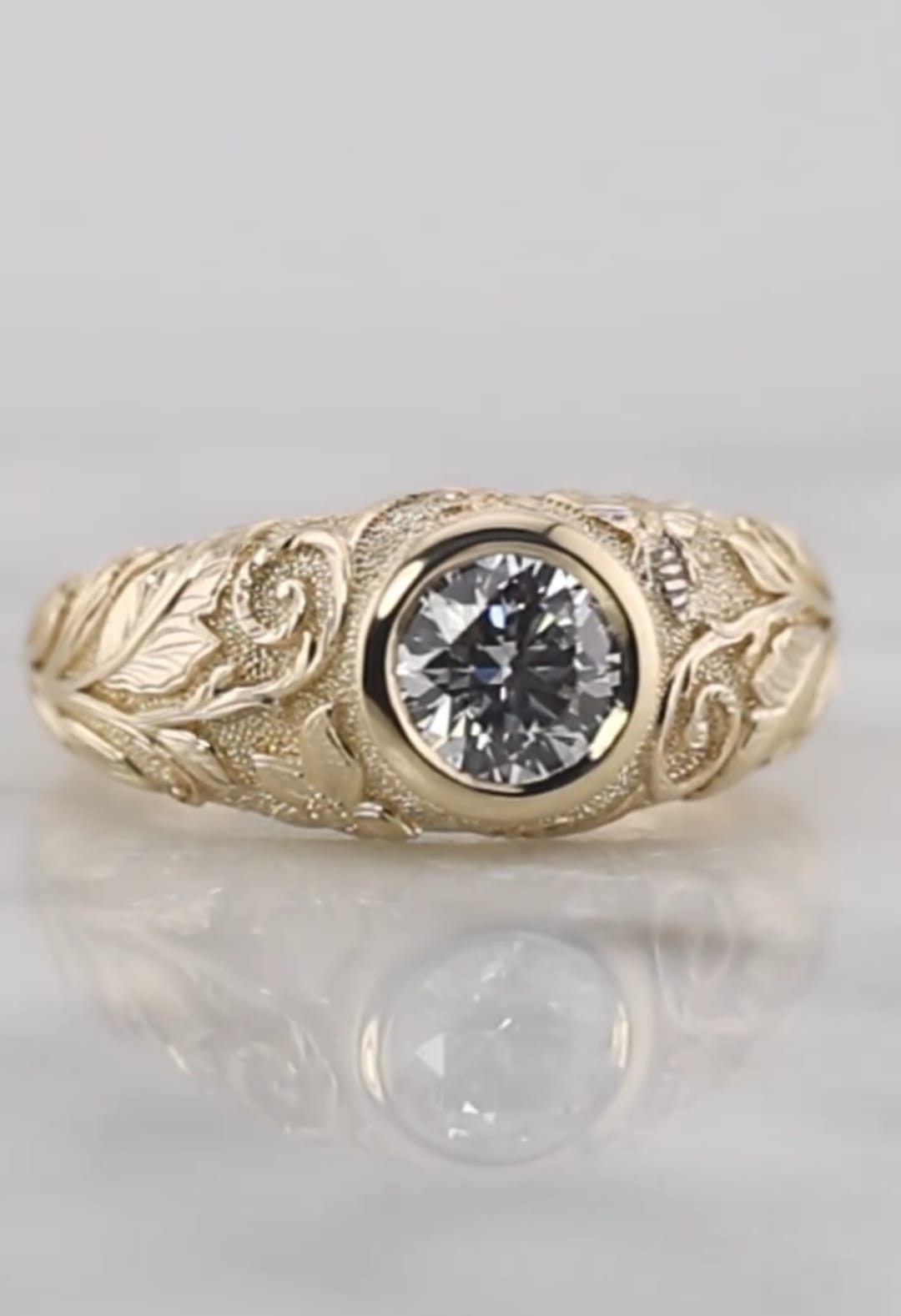 Top-down face-up view of a brilliant 2 carat round lab grown diamond set in a smooth yellow gold bezel