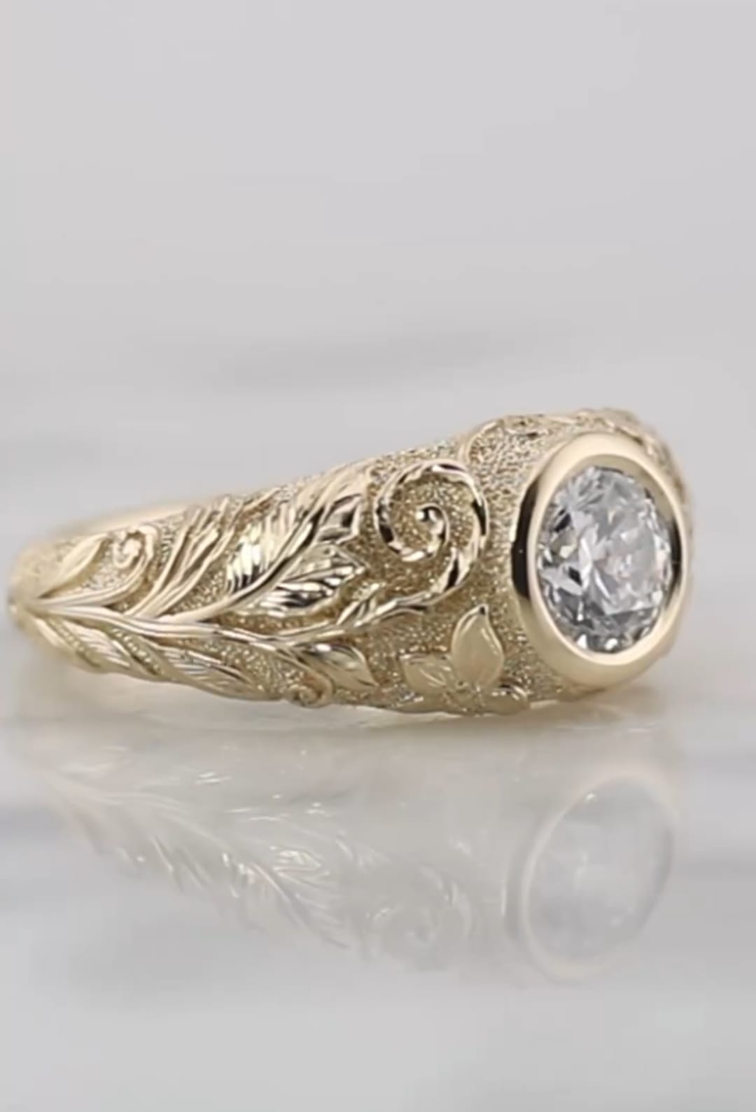 Profile shot of a nature-inspired yellow gold engagement ring showing carved leaves and smooth bezel edge