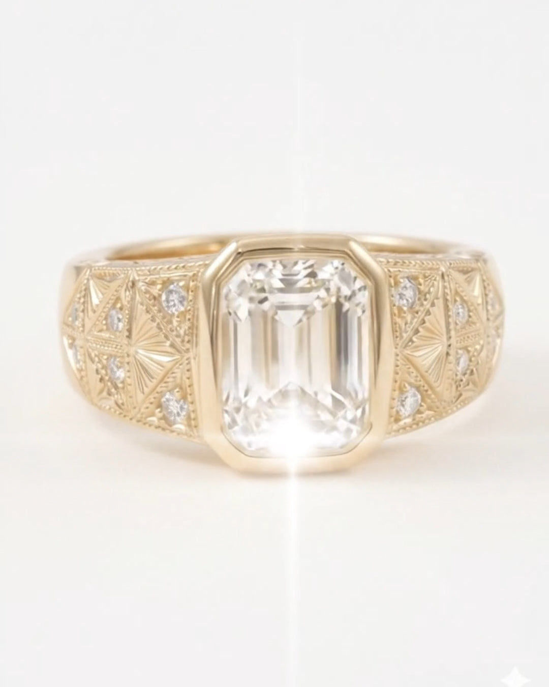 Front-facing shot of a vintage-inspired yellow gold ring showcasing a clear emerald-cut diamond center stone in a bezel setting, flanked by an intricately detailed, textured wide band with inset round diamonds.