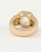 Rear view of a thick yellow gold ring band on a white background, showing the polished finish of the shank and the hollowed, decorative structure underneath the central setting.