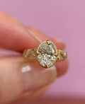 Top view showing a 3 carat oval lab grown diamond framed in a milgrain bezel setting in yellow gold