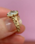 Angled view highlighting the botanical leaf and snake engraving on the wide yellow gold band