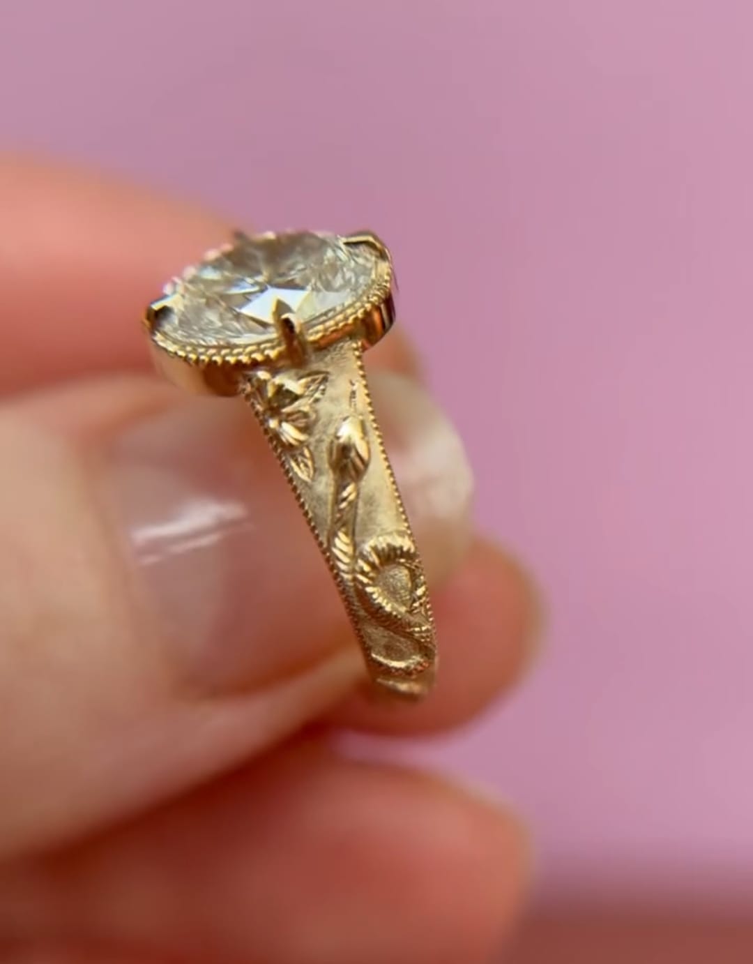 Angled view highlighting the botanical leaf and snake engraving on the wide yellow gold band