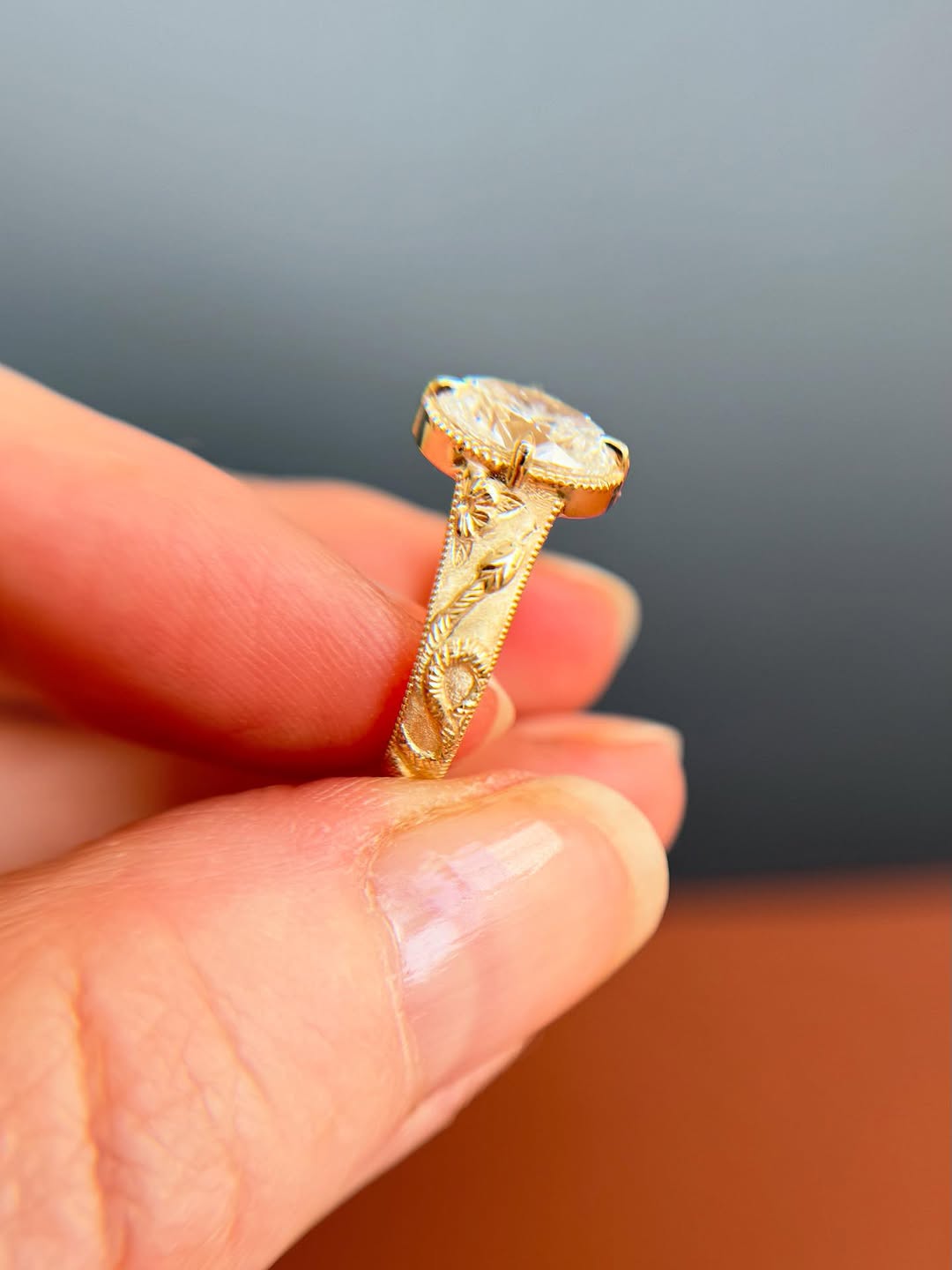 Side perspective highlighting hand-carved floral details on a satin-finished yellow gold band