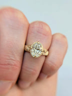 On-hand view of a 3 carat oval cut lab diamond engagement ring with an engraved snake yellow gold band