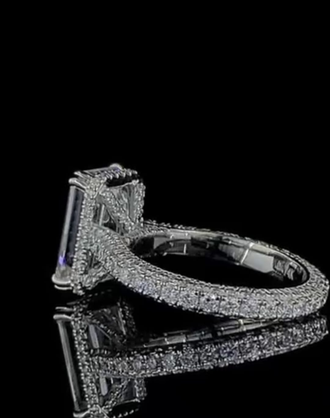 Close-up perspective showing the multi-row micro-pavé diamond band on a white gold emerald cut engagement ring