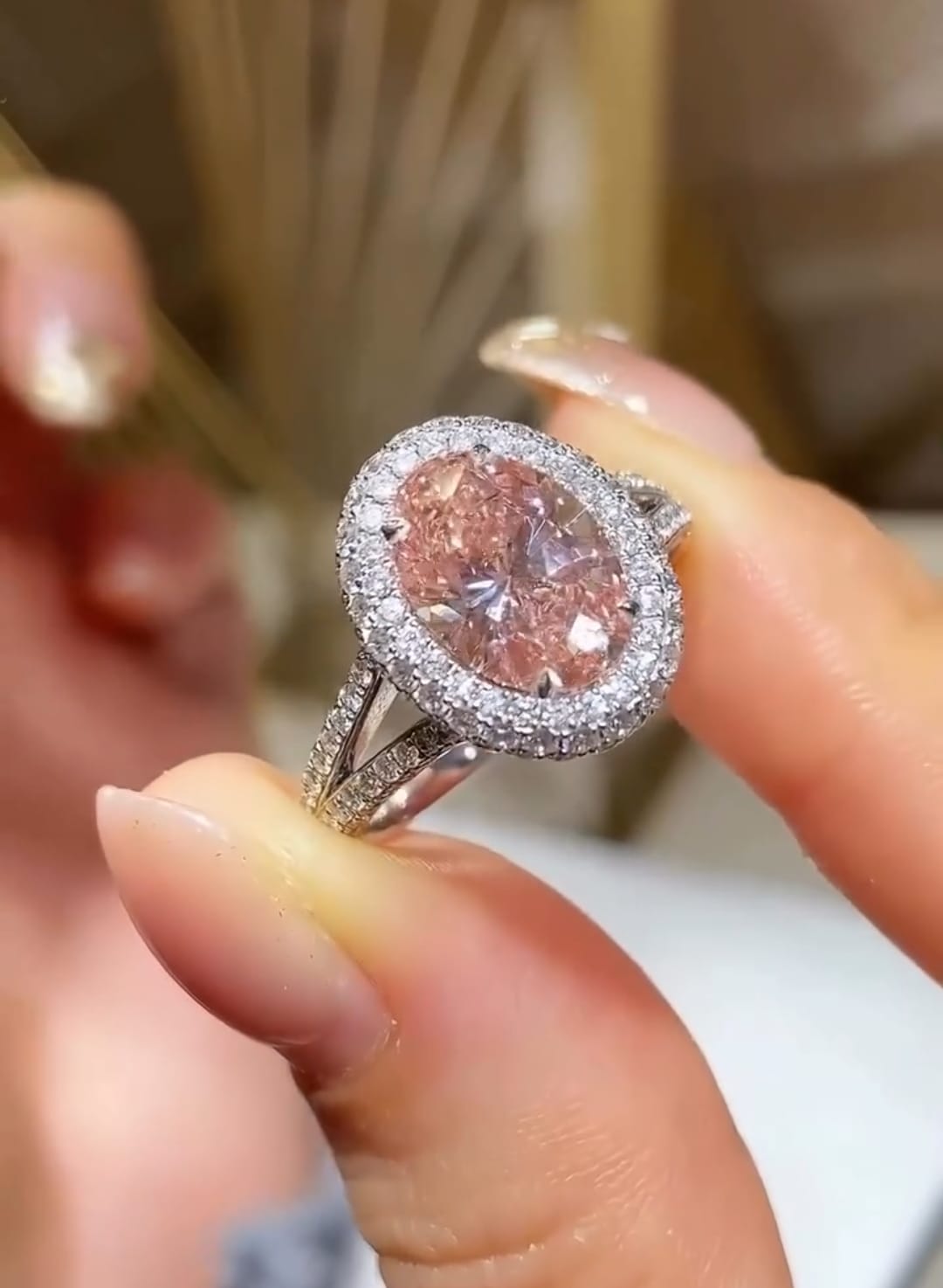 Handheld view highlighting the brilliant sparkle and double halo setting of a 3 Carat pink oval lab diamond ring