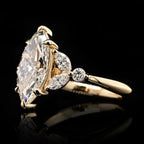 Angled side view showing the marquise cluster accents and secure claw prongs on yellow gold setting