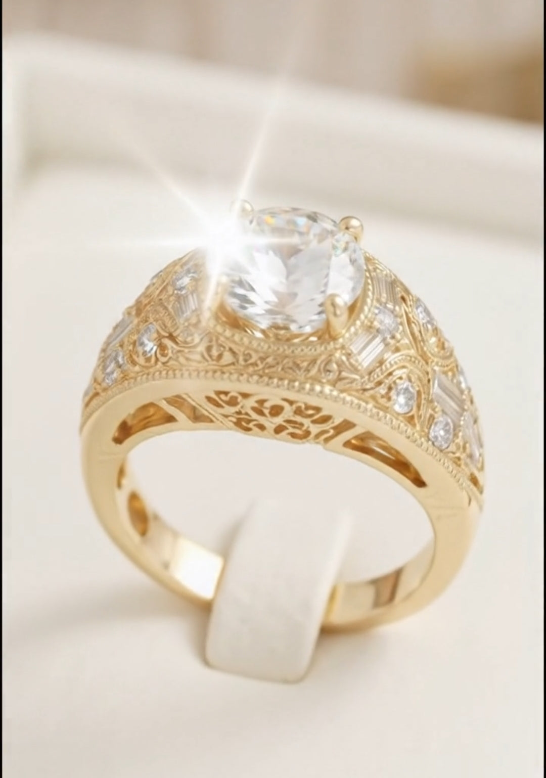 Top-down view of an Art Deco inspired gold statement ring showcasing a brilliant round-cut center stone set in a milgrain-bordered, wide filigree band with accent diamonds.