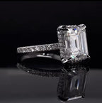 Angled front perspective view highlighting double claw prongs and hidden halo collar on an emerald lab diamond ring