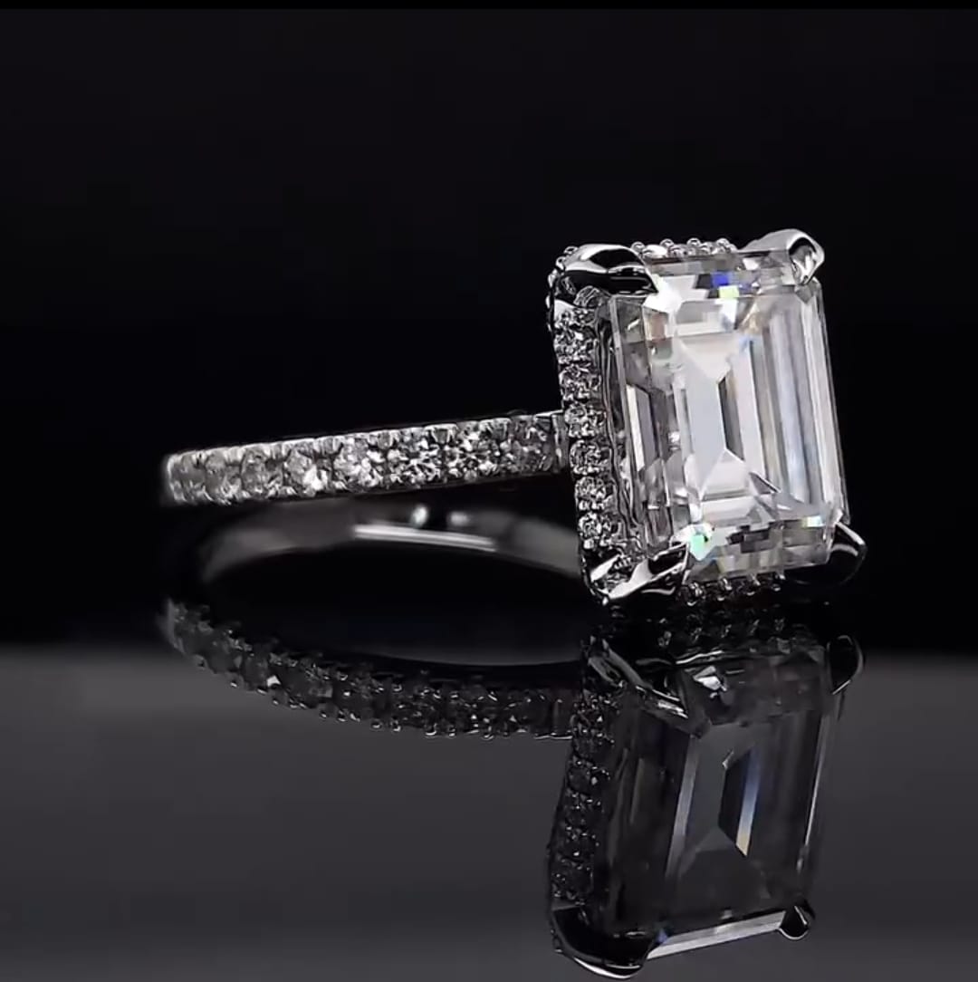 Angled front perspective view highlighting double claw prongs and hidden halo collar on an emerald lab diamond ring