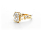 Front perspective view highlighting the emerald cut diamond and split shank band