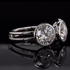 Side angle view of three-stone round cut lab diamond ring featuring bezel settings and a double rail band