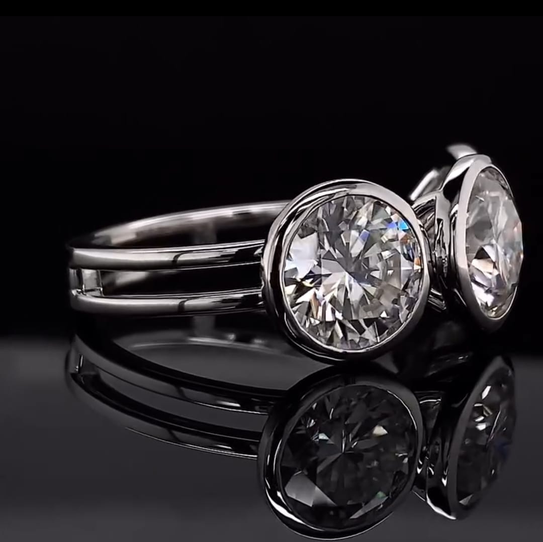 Side angle view of three-stone round cut lab diamond ring featuring bezel settings and a double rail band